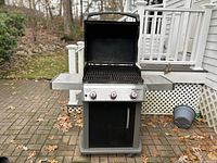 Front view of Weber Spirit gas grill with open lid showing cooking grate and three control knobs on front panel.