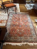 Full view of rug laid on hardwood floor beneath small furniture pieces, showing overall pattern and color.