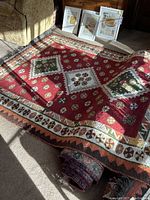 Full view of the Oriental style rug laid on a carpeted floor in natural light, showing its red background with large geometric medallions and floral motifs.