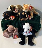 Six Beanie Babies placed on green fabric; includes Brown Batty, Bernie, two Dobys, Fortune, Amber.
