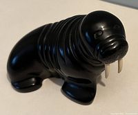 Front left angled view of black BOMA walrus figurine showing smooth carving and tusks
