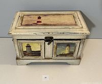 Front view of the wooden keepsake box showing lighthouse artwork on lid and front panels with latch.