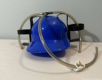 Front angle view of blue plastic novelty drinking helmet showing cup holders and attached tubing.
