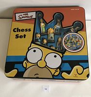 Tin box for Simpsons Chess Set with window showing several character chess pieces.