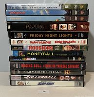 Stack of sports themed DVDs and Blu Ray movies, total 15 including football collection and titles like Caddyshack, Moneyball, and Raging Bull.