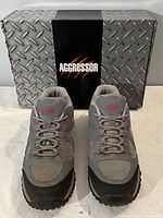 Front view of grey and pink steel toed shoes with black soles, showing minimal wear and laced up, positioned on top of Aggressor branded box.