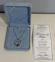 Necklace displayed in original light blue box alongside certificate of authenticity for Beacon of Hope pendant.