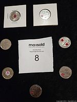 Eight Canadian quarters displayed on black background, some in white coin holders, showing commemorative poppy and breast cancer awareness designs