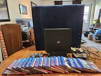 Overview of PS4 Pro console, three controllers, charging station and lined up game cases