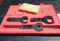 Set of three black metal belt tensioner wrenches in red plastic case with yellow instruction sheet on top.