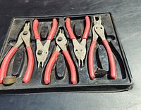 Set of five Snap-on C clip pliers with red handles in black plastic tray.