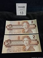 Front view of two 1986 Canadian two-dollar bills showing Queen Elizabeth II portrait, denomination 2, and Bank of Canada text.