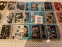 Four sheets of vintage music trading cards laid flat showing black and white and color photographs of musicians and bands.