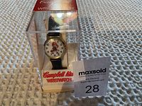 Campbell Kid wristwatch in original clear plastic container showing front dial and character design, placed on textured fabric surface.