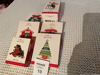 Photo of six Hallmark Keepsake Christmas ornaments in original boxes, arranged on a blanket surface.