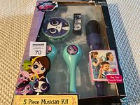 Photo showing the full 5 piece Littlest Pet Shop musician kit in original damaged packaging including tambourine, maracas, microphone, and music player.