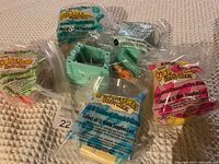 Five McDonald's The Flintstones Happy Meal toys still sealed in original plastic packaging, arranged on carpeted surface.