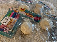 Photo showing four unpainted foam squishies and a set of five coloring markers in unopened packaging.
