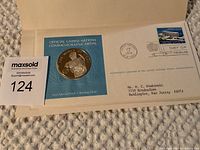 Photo of the commemorative silver medal on blue backing card with United Nations first day issue stamp and postmark with mailing address and certification.