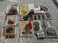 Front view of assorted collectible items spread on textured surface, featuring coins, stamps, postcards, buttons, novelty figurines, and small documents.