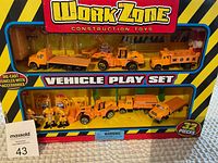 Front view of Work Zone construction vehicle play set in box showing multiple vehicles and accessories arranged in plastic display with yellow and black packaging.