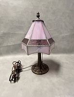 Front and side views of the stained glass table lamp showing the pink and purple stained glass panels, metal base, pull chain switch, and decorative finial on top.