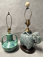 Full view of the two table lamps: Elephant-shaped Medalta Potteries Ltd lamp and green pottery lamp, showing brass fittings, ceramic bodies and overall shape.