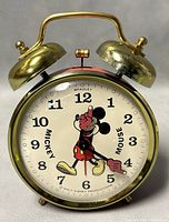 Front view of 1960s Bradley Mickey Mouse twin bell alarm clock showing clock face with full figure Mickey Mouse and brass bells.
