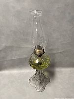 Full view of the 20.5 inch Queen Mary glass hurricane oil lamp showing yellow-green glass reservoir, ornate clear glass base, brass burner, and tall clear chimney.