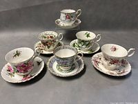 Photo showing all six Royal Albert teacup and saucer sets arranged in two rows, displaying the variety of floral patterns and gold rims.