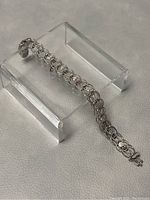 Full length view of the sterling silver bracelet displayed on a clear plastic stand showing length and link design