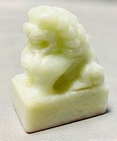 Close-up front angle of the small carved foo dog stone stamp showing detailed curly mane and facial features.