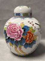 Front view of ginger jar showing large pink and orange flowers with detailed leaves and geometric design on lid.