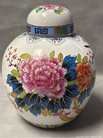 Front view of the hand-painted ginger jar showing floral motifs with pink, orange flowers, blue leaves with gold detail.