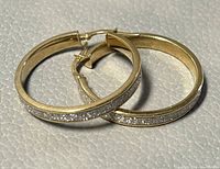 Side-on close view of both hoops showing pave diamond band along outer edge
