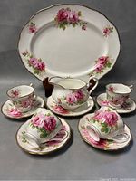 Full set showing 15 inch platter, gravy boat with under-plate, four teacup and saucers, arranged and photographed on grey background.