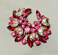 Front view of brooch showing gold-tone metal with pink and clear crystals in a floral and crescent motif.