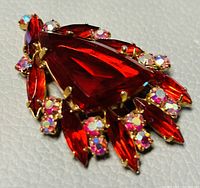 Close-up view of the brooch showing the large red teardrop crystal and surrounding smaller crystals and gold-tone setting.