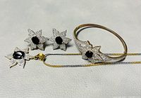 Photo showing the full set of jewelry including necklace with pendant, earrings, and bangle arranged on flat surface