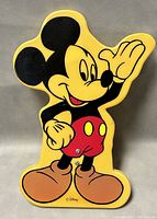 Close-up front photo of vintage acrylic Mickey Mouse lamp showing character details and colors including red shorts, brown shoes, black ears and yellow outline.