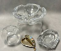 Photo showing the four items including the large and small glass ashtrays, glass bud vase, and the metal decorative leaf piece.