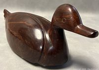 Close up front-side view showing carved beak, eye detail and wood grain of the rosewood duck sculpture.
