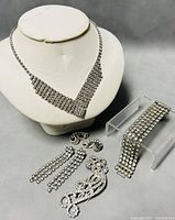 Full set arranged on display with all jewelry pieces visible showing necklace, earrings, bracelet, and hair clip.