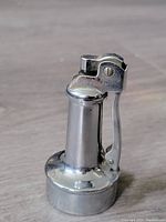Front side view of vintage Edwin chrome table lighter showing the lever ignition and brand marking.