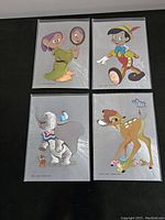 Four Disney Dufex foil postcards displayed showing front sides: Dopey with mirror, Pinocchio, Dumbo with Timothy Q. Mouse, and Bambi.