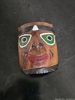 Front view of hand carved Native Kootenay mask highlighting facial features and paint colors.