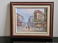 Framed oil painting depicting Parisian street with buildings, two figures walking and flower vendor. Signed by Burnett.