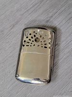 Front view of the vintage chrome hand warmer showing perforated top and smooth lower body.