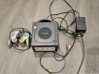 Nintendo GameCube console with controller, power adapter, and AV cables laid out showing all components