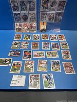 41 NFL player cards spread out on table showing various teams and player action shots with a note card stating 1991 NFL Cards.
